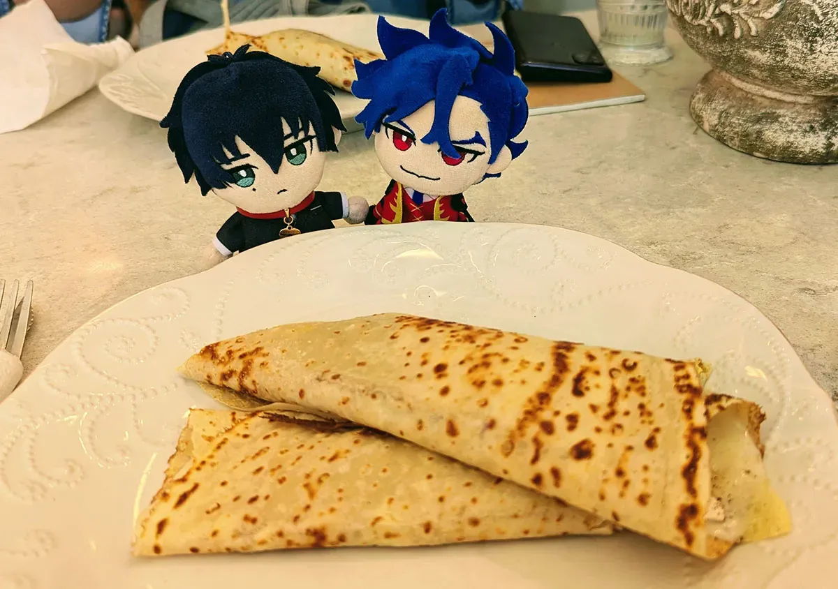 Tadashi and Ainosuke puppet charms sit behind a plate of savoury crepes